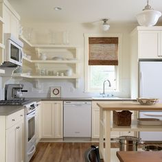 a kitchen with white cabinets and wooden floors