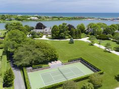 an aerial view of a tennis court in the middle of a lake and trees surrounding it