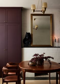 a dining room table with chairs and a mirror on the wall