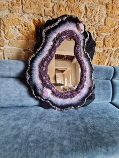 a mirror sitting on top of a blue couch next to a stone wall in a living room