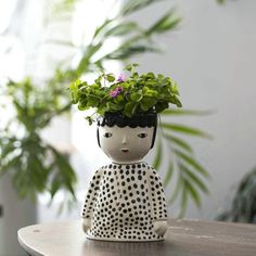 a ceramic figurine sitting on top of a wooden table next to a potted plant