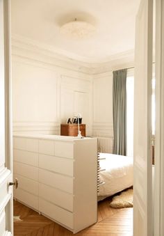 a bedroom with white furniture and wood floors