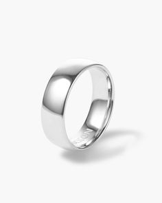 a white gold wedding ring on a plain surface, with the top half slightly closed