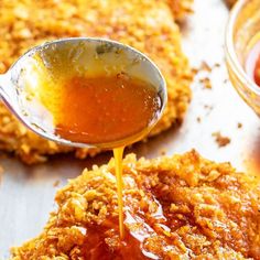 a spoon drizzling honey onto some fried chicken patties with ketchup