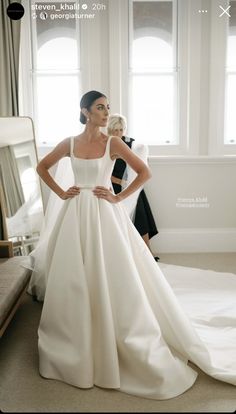 a woman standing in front of a mirror wearing a wedding dress with straps and pockets