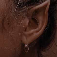 a woman's ear is shown with two small hoops on the end of it