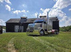 a large semi truck parked in front of a barn