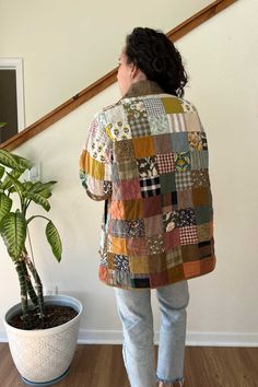 a woman standing in front of a potted plant next to a stair case that has a patchwork design on it