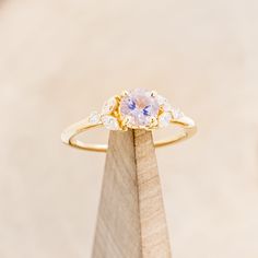 a close up of a ring on top of a piece of wood with diamonds around it