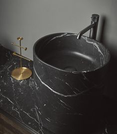 a bathroom sink with a black marble counter top and gold faucet on the side