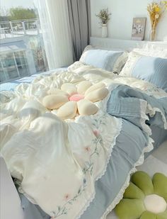 a bed with blue and white comforters on top of it next to a window