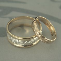 two gold wedding rings sitting on top of each other