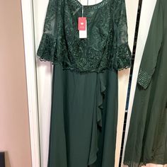 a green dress hanging on a hanger in front of a closet with other clothes