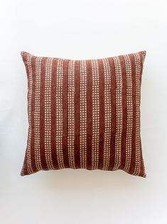 a brown and white striped pillow sitting on top of a wall