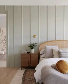 a bed with white sheets and pillows in a bedroom next to a wooden dresser topped with a potted plant