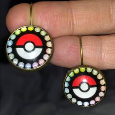 a pair of earrings that have been painted with different colors and designs on them, sitting in someone's hand