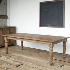 a wooden table sitting on top of a hard wood floor next to a chalkboard