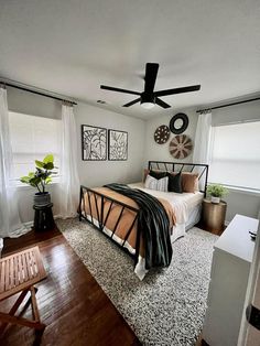 a bed room with a neatly made bed next to a window and a ceiling fan