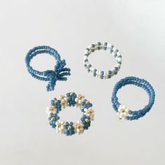 three bracelets and two rings with pearls on them are sitting next to each other