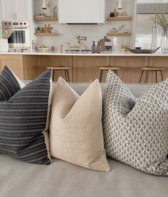 four pillows sitting on top of a couch in a living room next to a kitchen