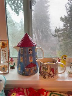 a coffee pot sitting on top of a window sill next to a mug and other items