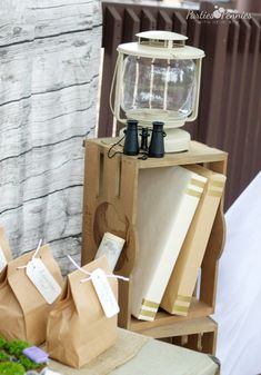 a table topped with boxes and bags next to a lamp on top of a wooden stand