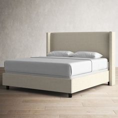 a bed with white sheets and pillows in a room that has wood flooring on it