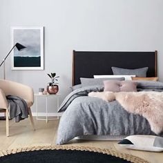 a bedroom with grey walls and white furniture, including a bed covered in fluffy blankets