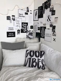 a white bed topped with lots of pillows next to a wall covered in black and white pictures