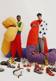 two men standing next to each other in front of stuffed animals and shoes on the floor