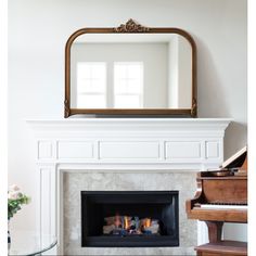 a living room with a piano and a mirror on the wall over the fire place