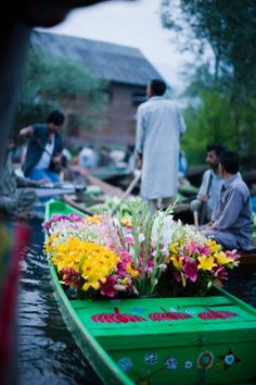 people are on boats with flowers in the water and one person is standing near by