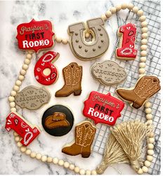 decorated cookies are arranged in the shape of cowboy boots and boots on a marble surface