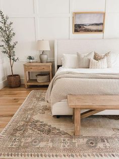 a bedroom with a bed, nightstands and a rug on the floor in front of it