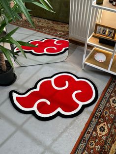 two red and black rugs sitting on top of a floor next to a potted plant