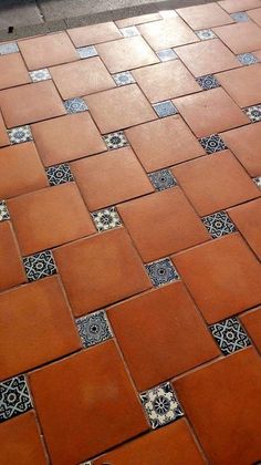 an orange and black cat sitting on top of a red tiled floor next to a white fire hydrant