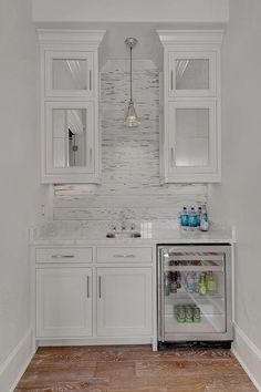 a kitchen with white cabinets and an icebox in the center, along with wooden floors