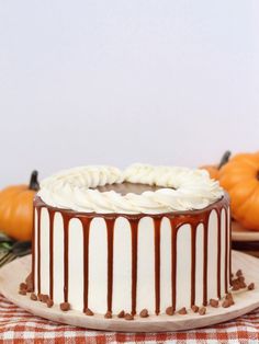 a cake with white frosting and chocolate drizzled on top sitting on a plate