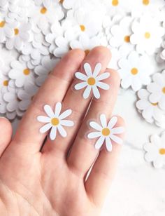 someone is holding their fingers in front of some daisies