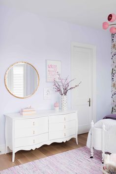 a bedroom with white furniture and pink decor on the walls, along with a floral wallpaper