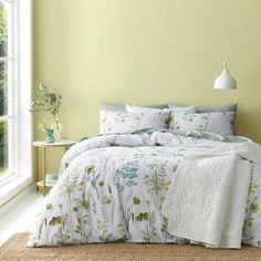 a bed in a room with yellow walls and flowers on the bedspread next to a window