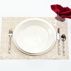 a white plate and silverware on a place mat next to a red napkin, fork and knife