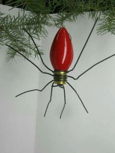 a red spider sitting on top of a white wall next to a green tree branch