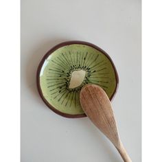 a wooden spoon resting in a ceramic bowl with kiwi slices on it's side