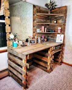 a desk made out of wooden pallets in front of a large mirror and shelves