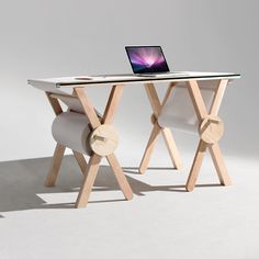 a laptop computer sitting on top of a wooden desk next to a white chair and table