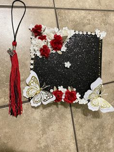 a piece of paper with flowers and butterflies on it next to a red tassel