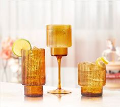 three yellow glass cups with lemon wedges on the side