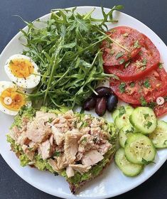 a white plate topped with meat, vegetables and eggs