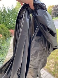 a person holding a black trash bag in their hand